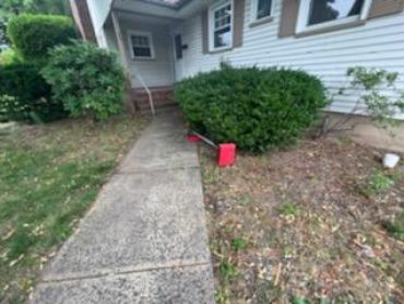 Sweep equipment on the ground beside the front walkway of a home